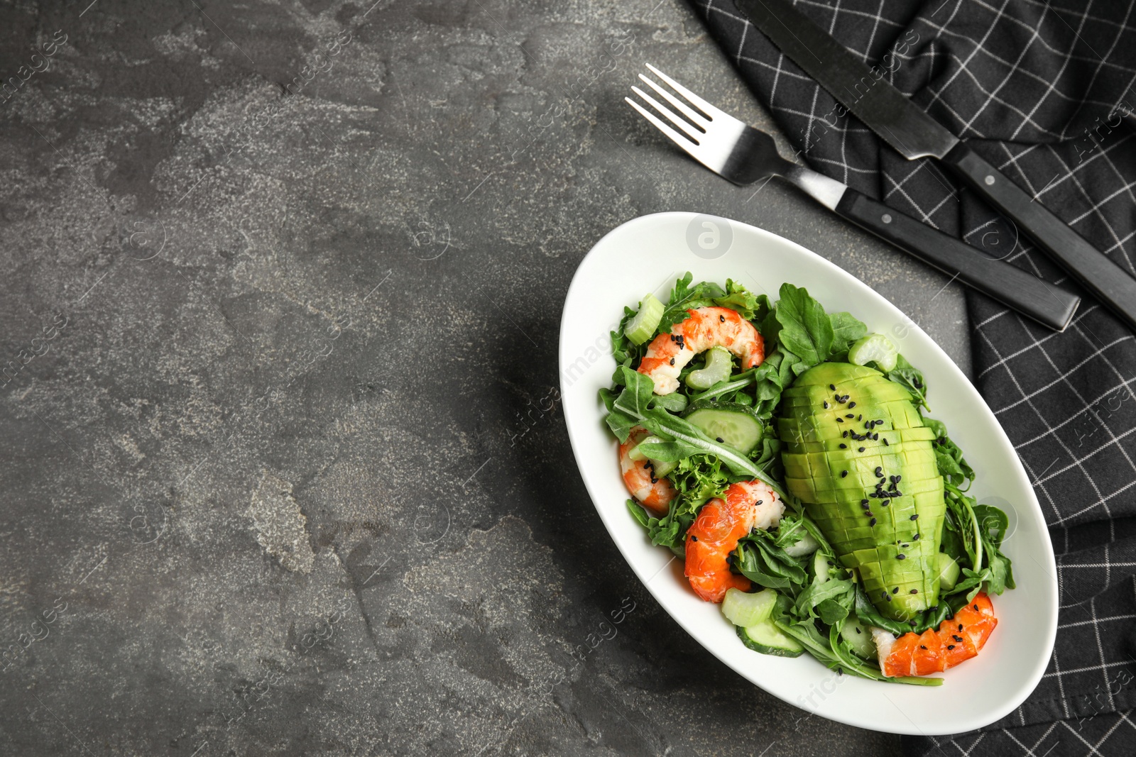 Photo of Delicious avocado salad with shrimps in bowl on grey table, flat lay. Space for text