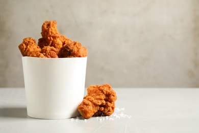 Tasty deep fried chicken pieces on white table. Space for text