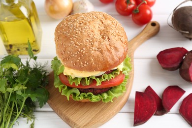 Photo of Delicious vegetarian burger and ingredients on white wooden table