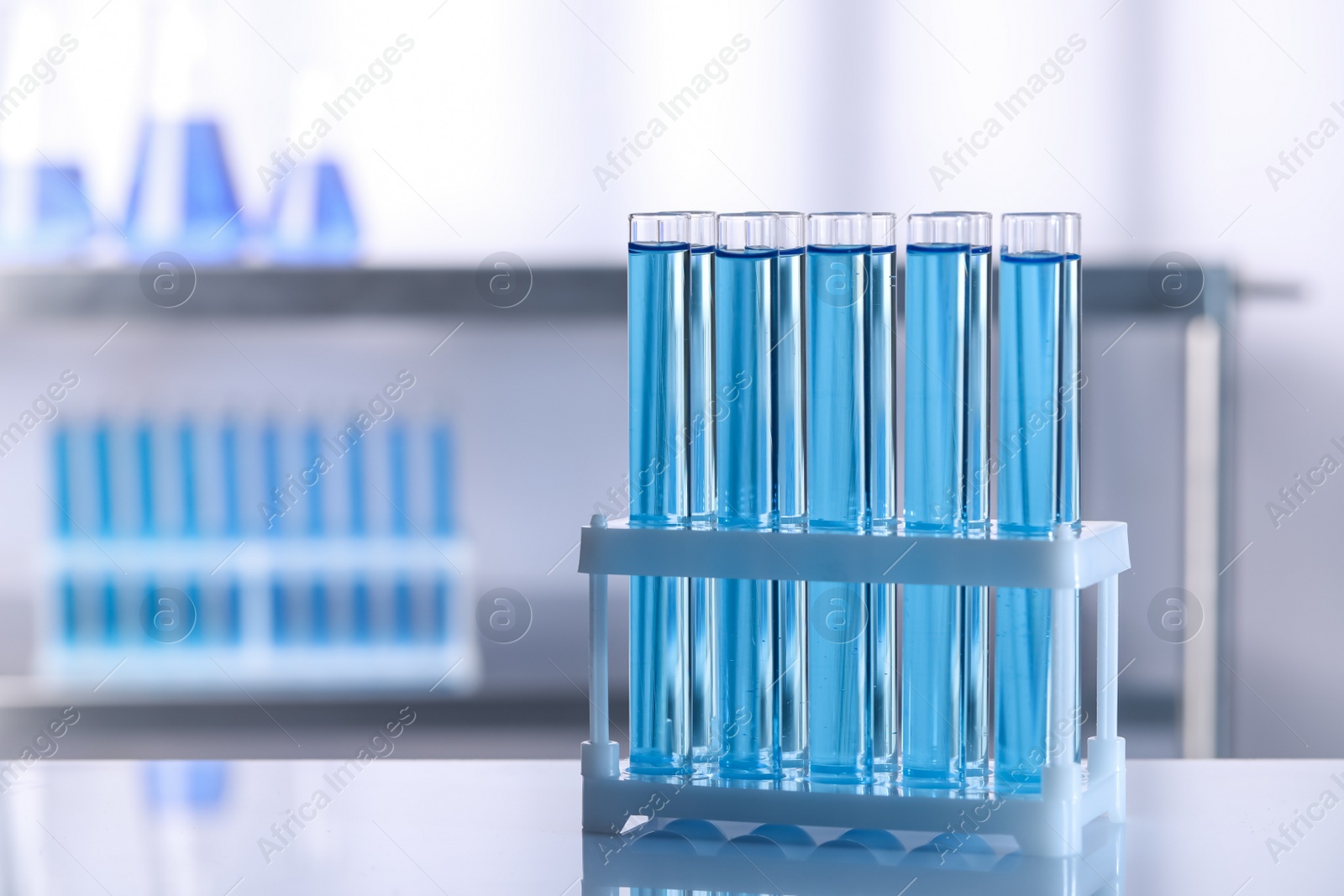 Photo of Test tubes with reagents on table in laboratory, space for text