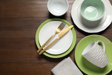 Photo of Beautiful ceramic dishware, cup and cutlery on wooden table, flat lay. Space for text