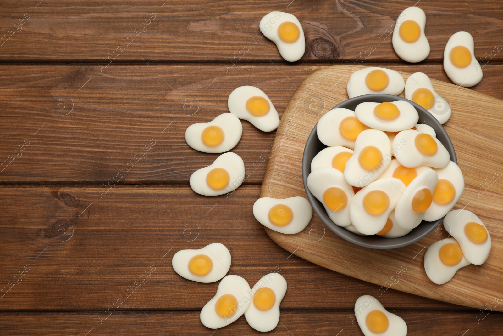 Photo of Delicious gummy fried eggs shaped candies on wooden table, flat lay. Space for text