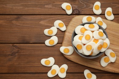 Delicious gummy fried eggs shaped candies on wooden table, flat lay. Space for text