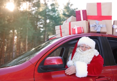 Authentic Santa Claus driving car with gift boxes, view from outside