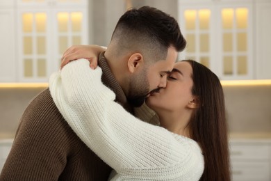 Affectionate young couple kissing and hugging in kitchen