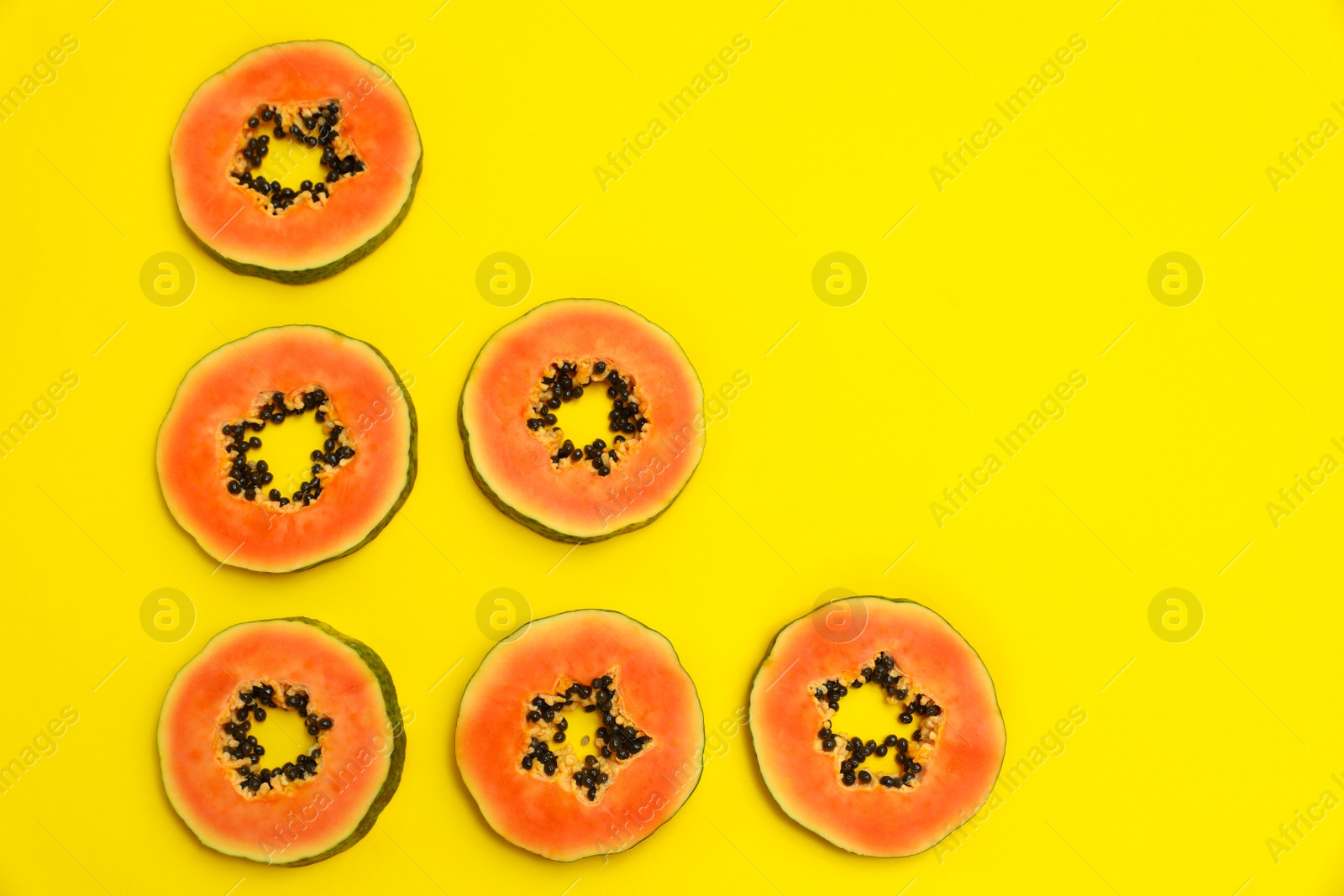 Photo of Flat lay composition with slices of papaya on yellow background, space for text