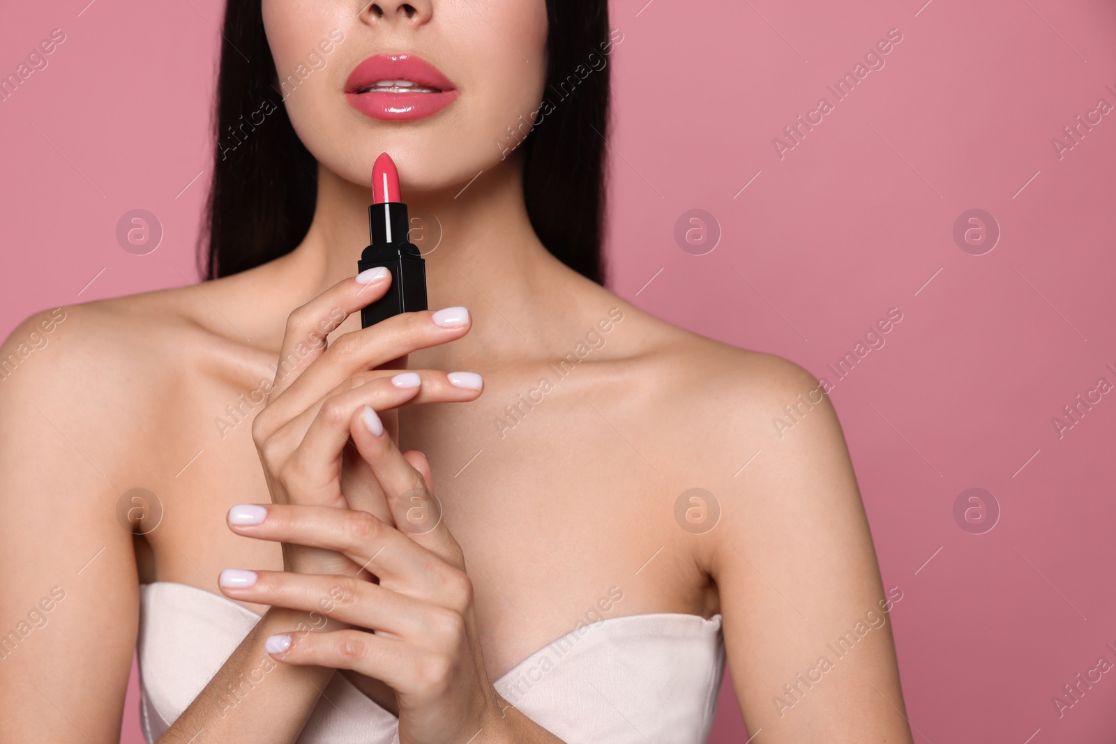 Photo of Young woman with beautiful makeup holding glossy lipstick on pink background