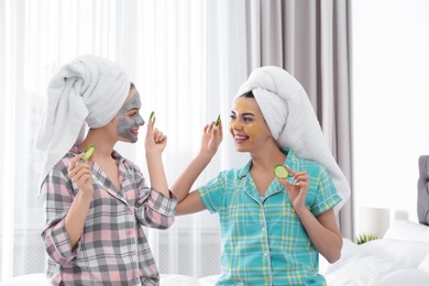 Photo of Young friends with facial masks having fun in room at pamper party