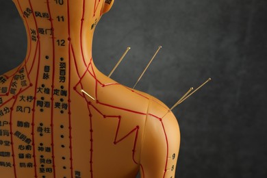 Photo of Acupuncture - alternative medicine. Human model with needles in shoulder near dark grey background, back view