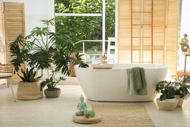 Photo of Stylish bathroom interior with modern tub and beautiful houseplants