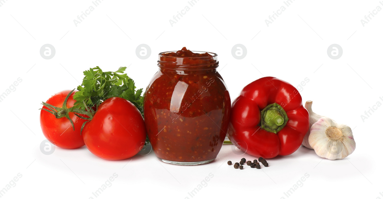 Photo of Glass jar of tasty adjika and ingredients on white background