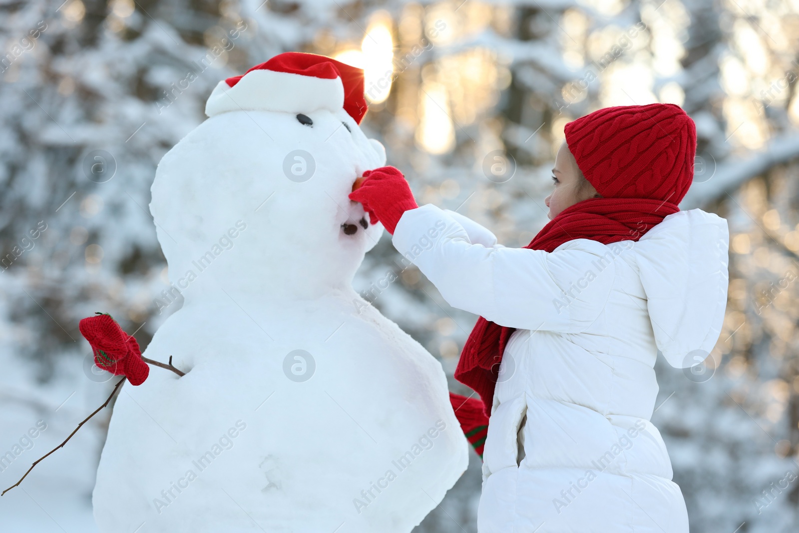 Photo of Cute little girl making snowman in winter park