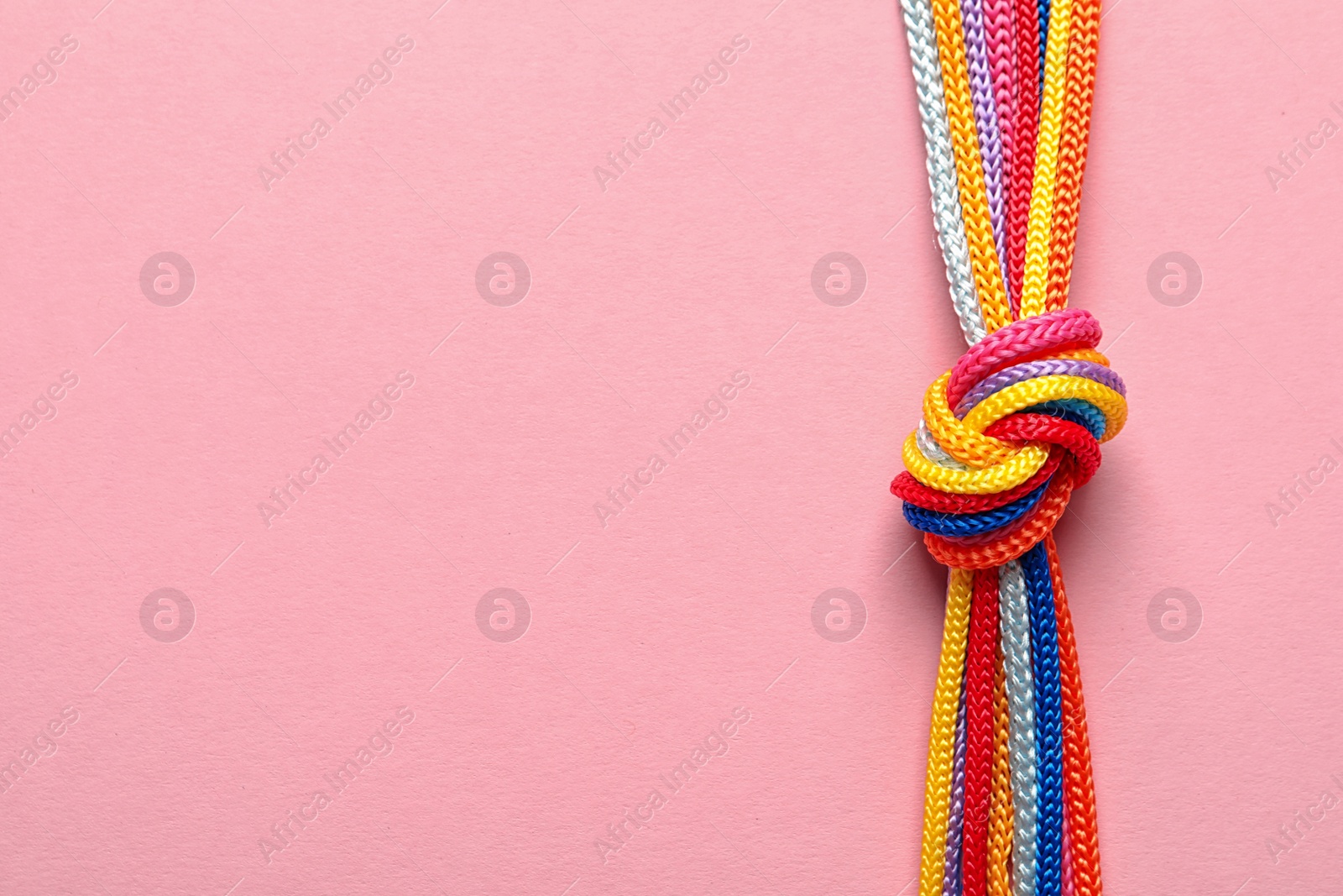 Photo of Different ropes tied together with knot on color background. Unity concept