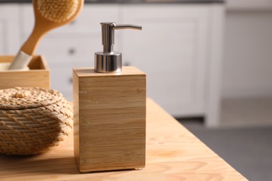 Photo of Dispenser with liquid soap near wicker box on wooden table in bathroom, space for text