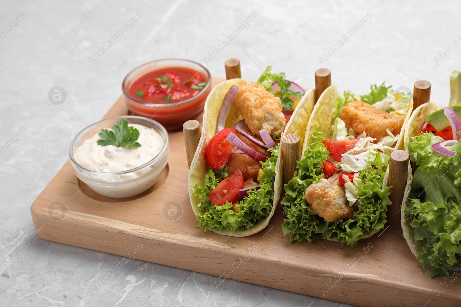 Photo of Delicious fish tacos served on grey marble table