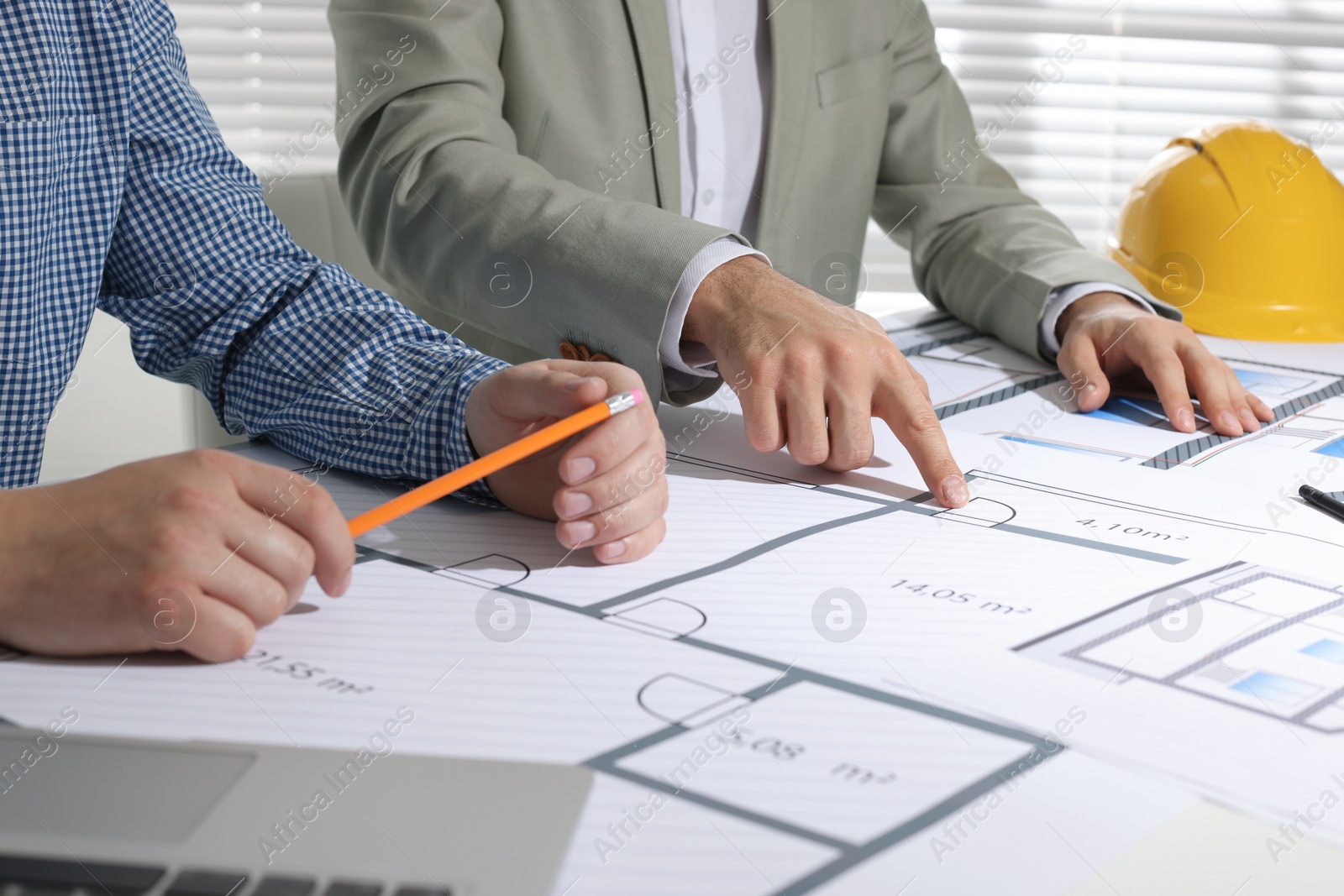 Photo of Architects working with construction drawings at table in office, closeup