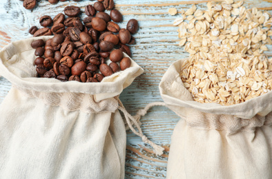 Photo of Cotton eco bags with oat flakes and coffee beans on wooden table, flat lay