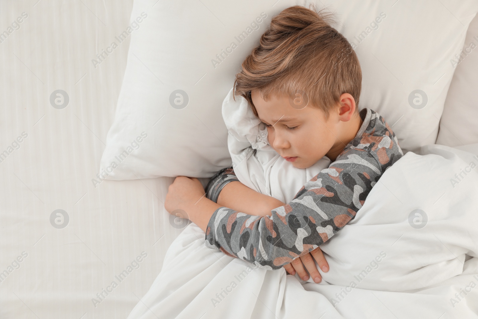 Photo of Cute boy sleeping in bed, above view