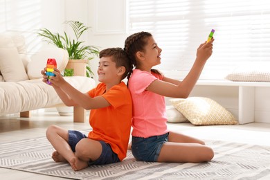 Children playing with pop it fidget toys on floor at home