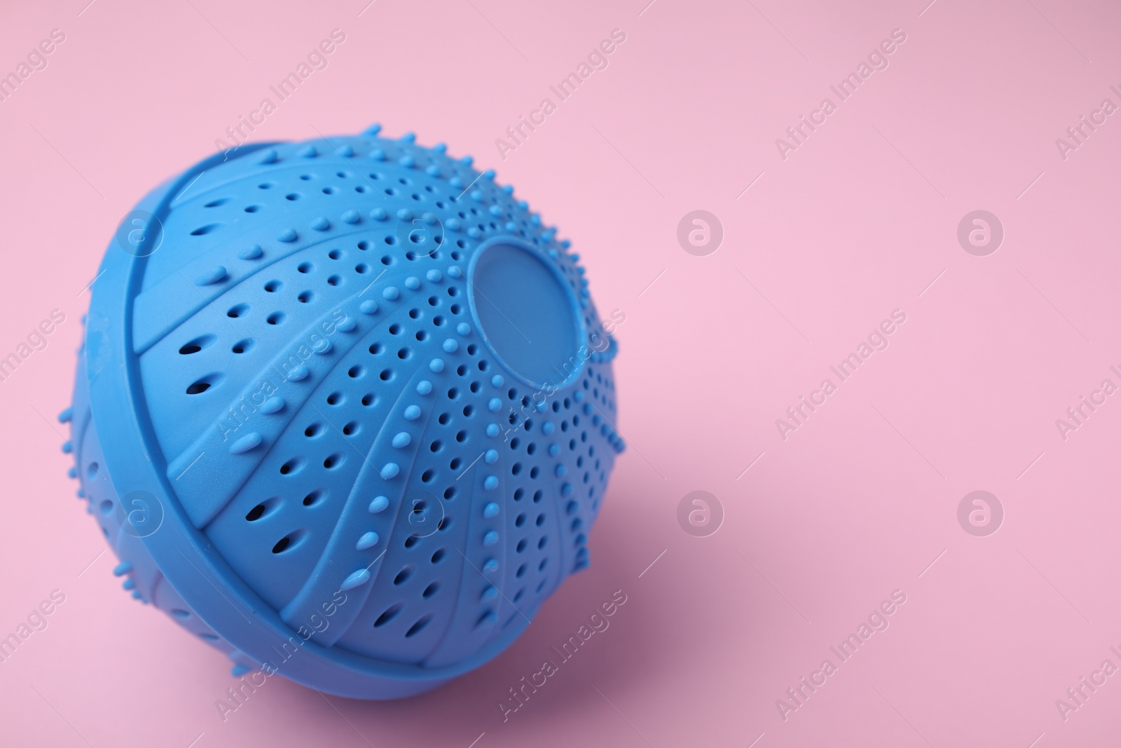 Photo of Laundry dryer ball on pink background, space for text