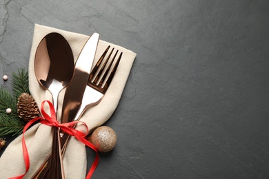 Photo of Cutlery set and festive decor on black slate table, flat lay with space for text. Christmas celebration