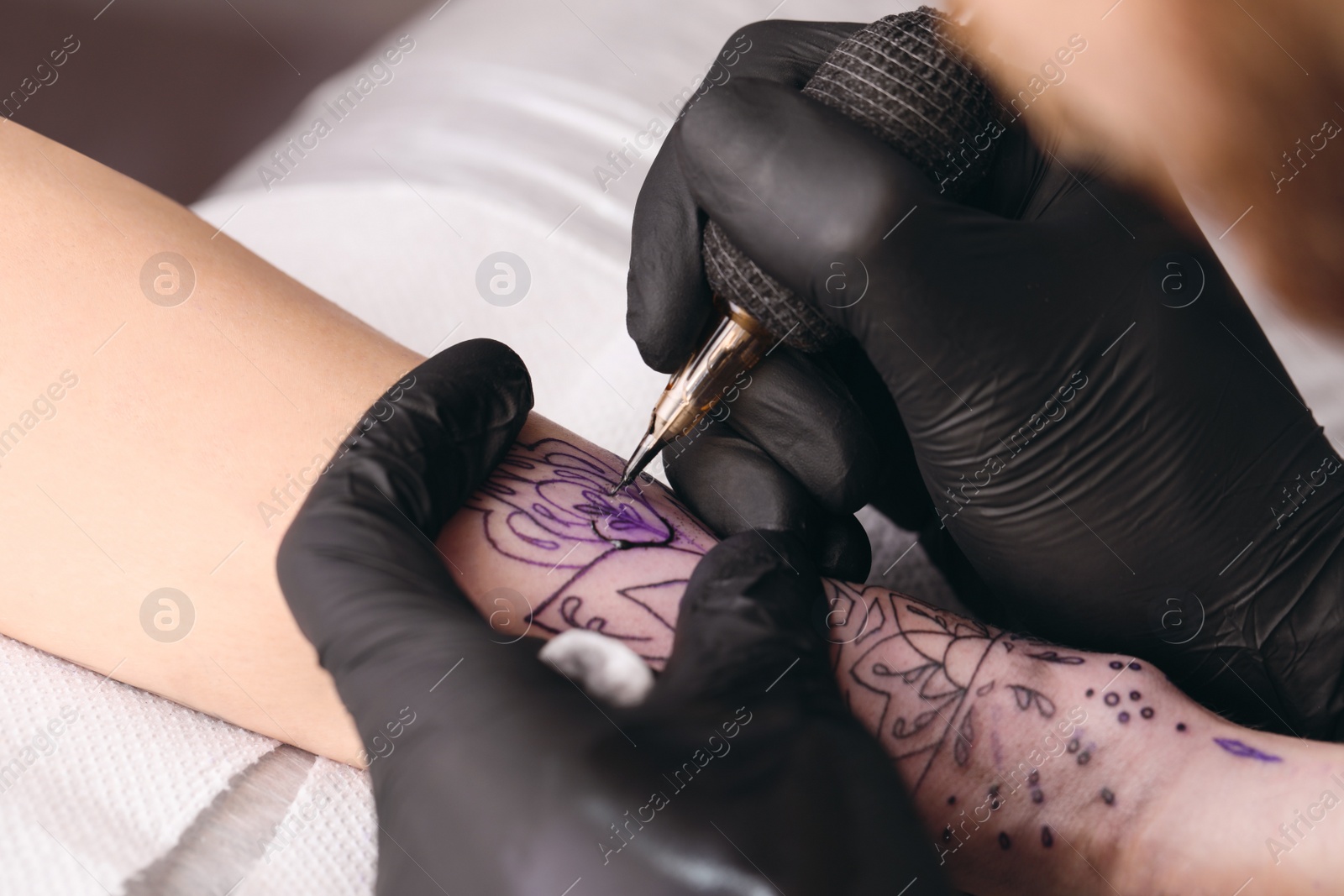 Photo of Professional artist making tattoo on hand at table, closeup