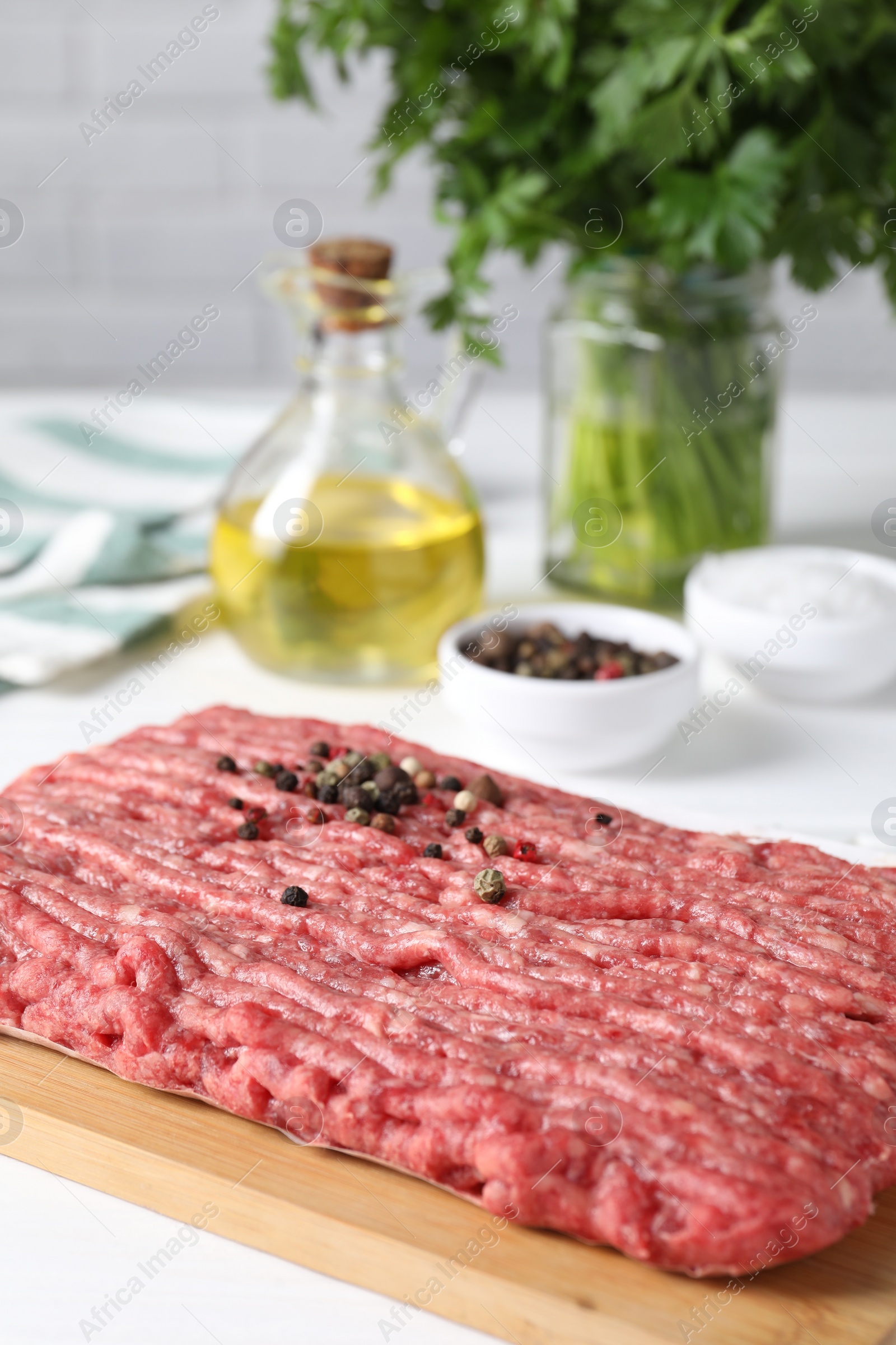 Photo of Raw ground meat, spices, oil and parsley on white table