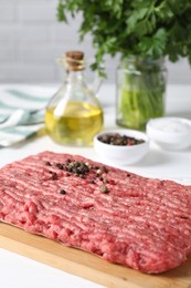 Photo of Raw ground meat, spices, oil and parsley on white table