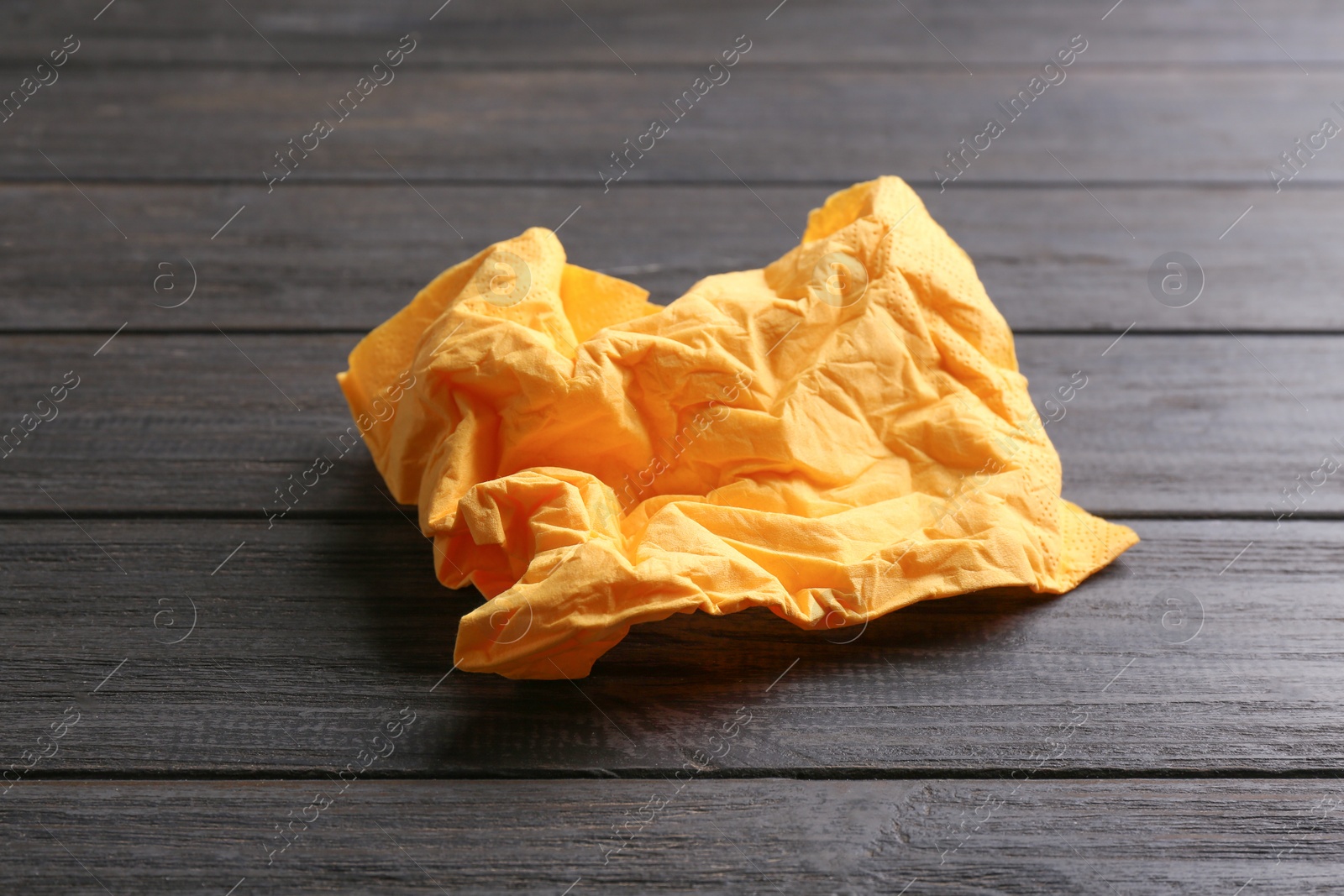 Photo of Crumpled paper napkin on wooden background. Personal hygiene