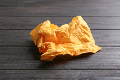 Photo of Crumpled paper napkin on wooden background. Personal hygiene