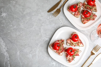 Delicious bruschettas with prosciutto served on grey table, flat lay. Space for text