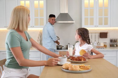Photo of Happy family eating together in modern kitchen