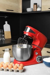 Photo of Modern stand mixer and ingredients on table in kitchen. Home appliance