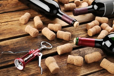 Photo of Bottles with wine, corkscrew and corks on wooden table