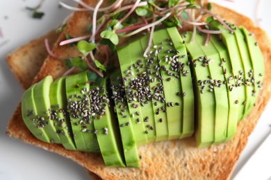 Photo of Tasty toast with avocado, sprouts and chia seeds, closeup