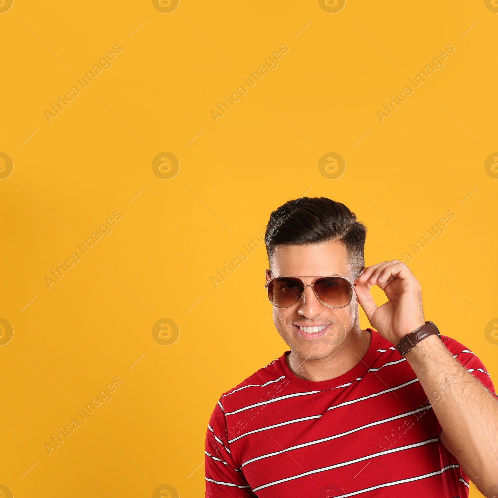 Photo of Handsome man wearing sunglasses on yellow background. Space for text