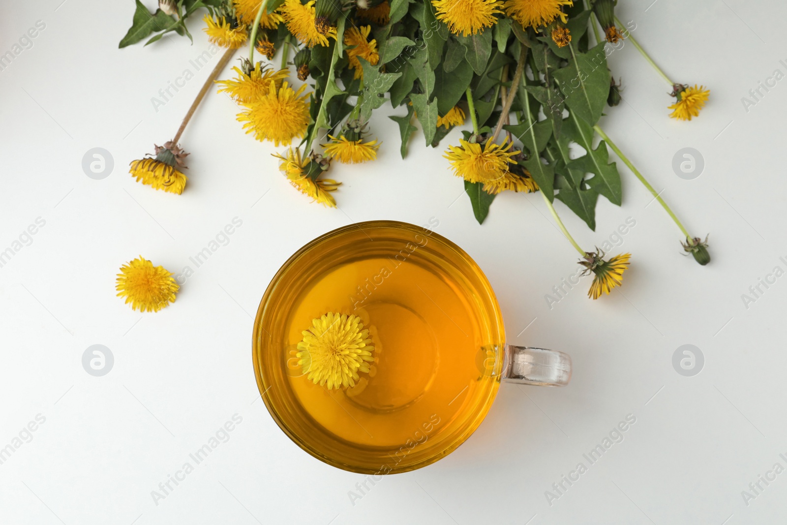 Photo of Delicious fresh tea and beautiful dandelion flowers on white background, top view