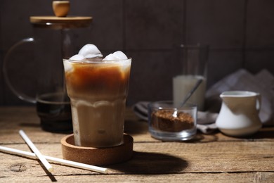 Photo of Refreshing iced coffee in glass and straws on wooden table