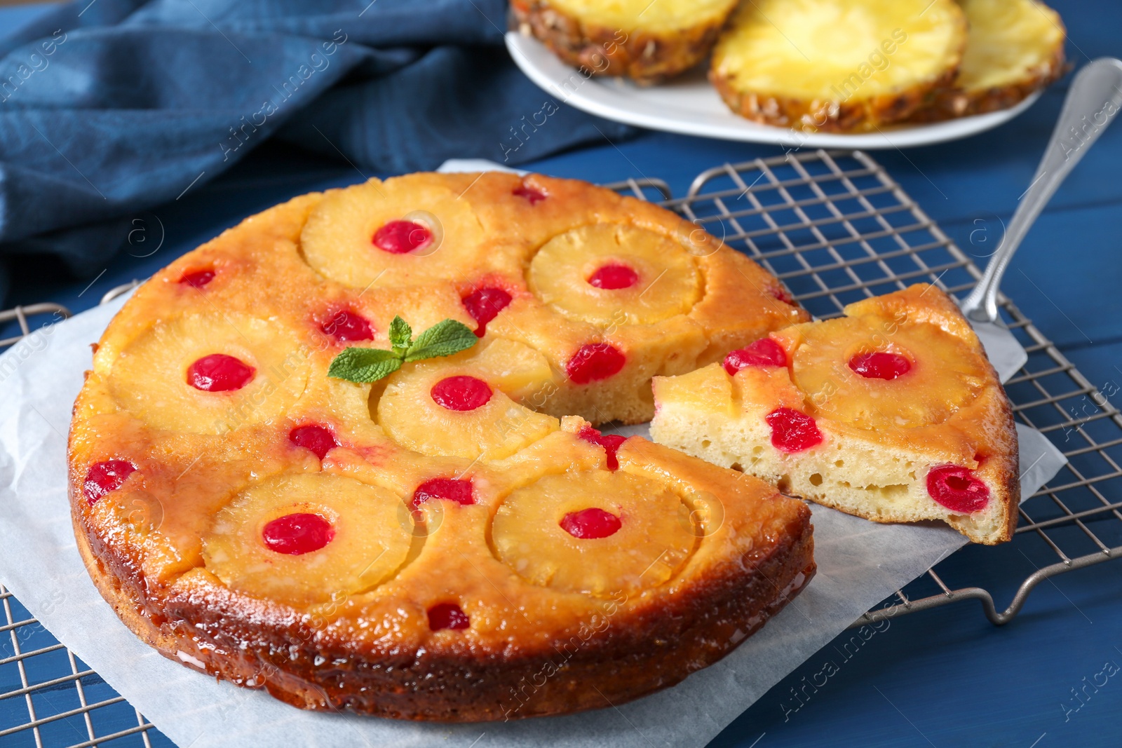 Photo of Delicious cut pineapple pie with cherry on blue table, closeup