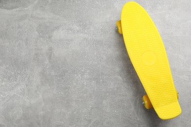 Photo of Yellow skateboard on grey stone background, top view. Space for text