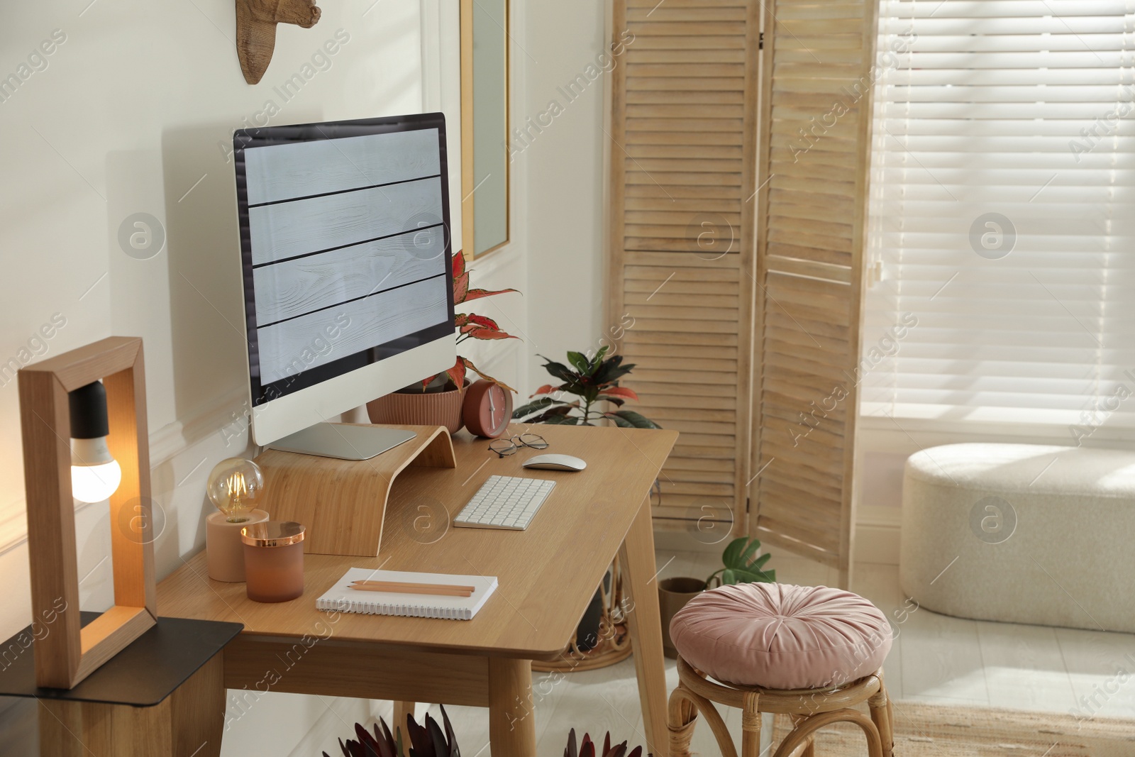 Photo of Comfortable workplace with modern computer and beautiful plants in room. Interior design