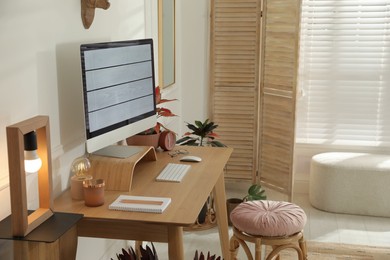 Photo of Comfortable workplace with modern computer and beautiful plants in room. Interior design