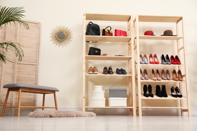 Wooden shelving unit with different shoes and accessories in stylish room interior