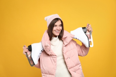 Photo of Happy woman with ice skates on yellow background