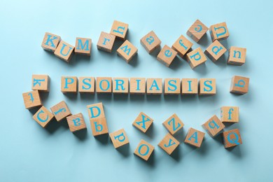 Word Psoriasis made of wooden cubes with letters on light blue background, flat lay
