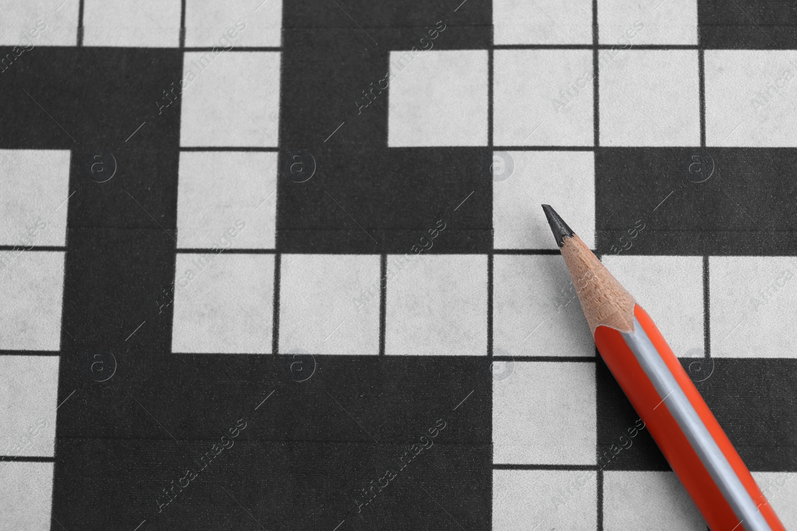 Photo of Pencil on blank crossword, top view. Space for text