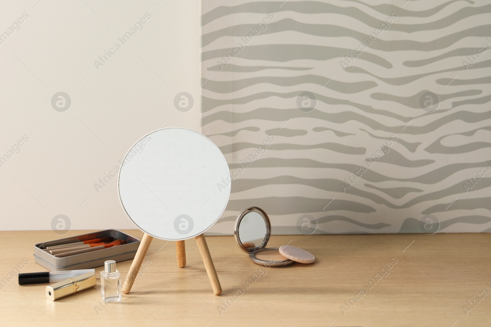 Photo of Mirror, makeup products and perfume on wooden dressing table in room. Space for text