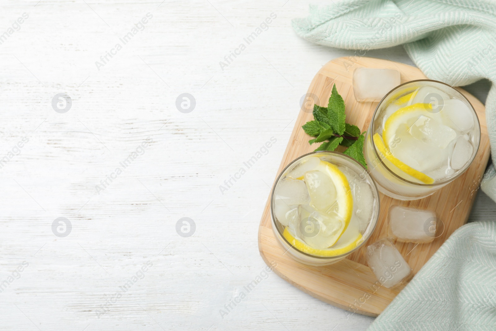 Photo of Glasses of cocktail with vodka, ice and lemon on white wooden table, top view. Space for text