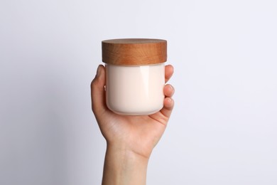 Woman holding jar of face cream on white background, closeup