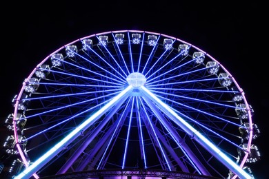 Beautiful glowing Ferris wheel against dark sky, low angle view